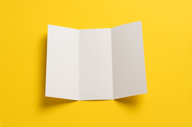 Ulotka składana na żółtym tle symbolizująca skuteczną reklamę drukowaną